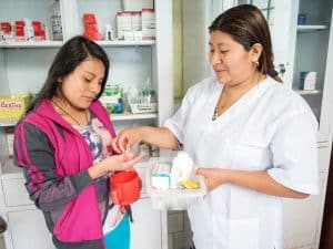 Joven recibe medicinas de parte de una enfermera en el Hogar de Vida. Los residentes tienen atención médica gracias al apoyo de Maryknoll. (Nile Sprague/Perú)