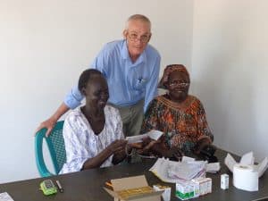 El Padre de Maryknoll John Barth con Natalina Itwari y Munira Fyagos, personal de la clínica de ojos. (Cortesía del Padre John Barth)