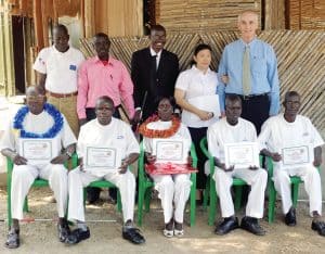 Cinco adultos impedidos de la vista (sentados) muestran certificados como masajistas, que recibieron en un programa de entrenamiento laboral iniciado por el Padre Barth.