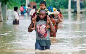 Cartas a Maryknoll- image Un hombre alza a su hijo en medio de las aguas, durante las inundaciones en Agartala, India. (CNS/India)