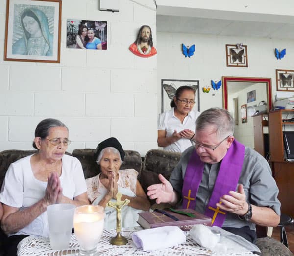 El sacerdote y agentes pastorales visitan a María Alicia Guzmán, 92, para rezar juntos, como parte de su ministerio de visita a los enfermos
