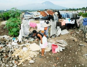 amor preferencial por los Pobres- columna- Una mujer salvadoreña trabaja frente a su humilde hogar en Soyapango, en las afueras de San Salvador. (CNS/El Salvador)