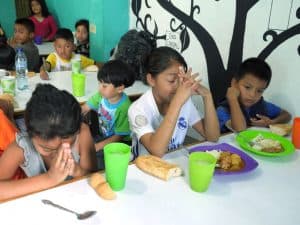 una niña hace una bendición en la mesa antes de comer en Guatemala.