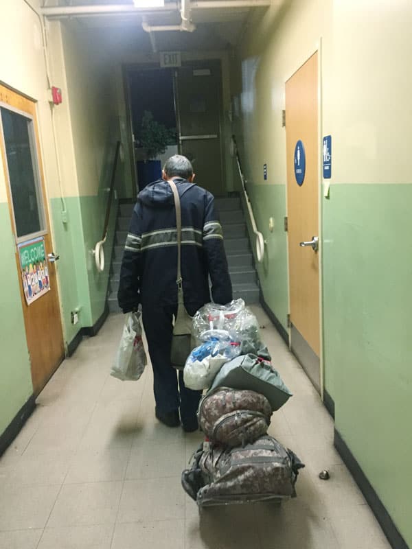 Después de cenar en el comedor del colegio parroquial, un desamparado con sus pertenencias se dirige hacia la parroquia Misión Dolores, en Boyle Heights, para poder descansar. (Giovana Soria/Los Ángeles)