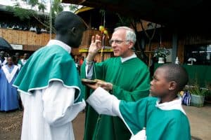 Llamados, enviados, transformados: 100 años de Envío a Misión: Durante una Misa en una aldea de Kenya, el Padre Maryknoll Robert Jalbert da la comunión a un joven. (Sean Sprague/Kenya)