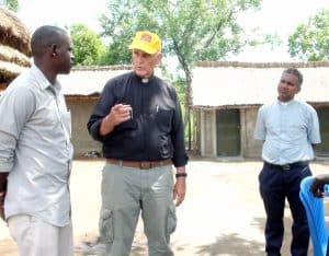 Richard Robert Odokonyero, dcha., conversa con el Padre Maryknoll John Barth, Padre Salesiano Jeffrey Jegan y un feligrés de la parroquia en el asentamiento de Palabek.