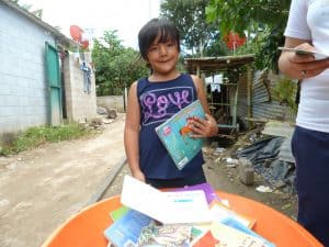 Leslie toma un libro prestado de la biblioteca rodante en la comunidad Esperanza en San Salvador, El Salvador. (Rick Dixon/El Salvador)