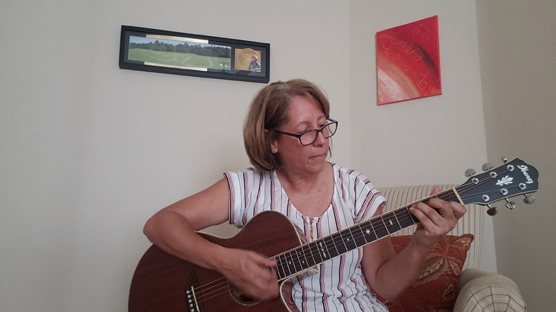 Después de asistir al webinar de Maryknoll y reflexionar sobre un pasaje de la biblia, Iris Lai-Zayas se inspiró para componer y grabar una canción. Ella está tocando la guitarra y cantando en casa durante este tiempo de coronavirus. (Iris Lai-Zayas/Texas)