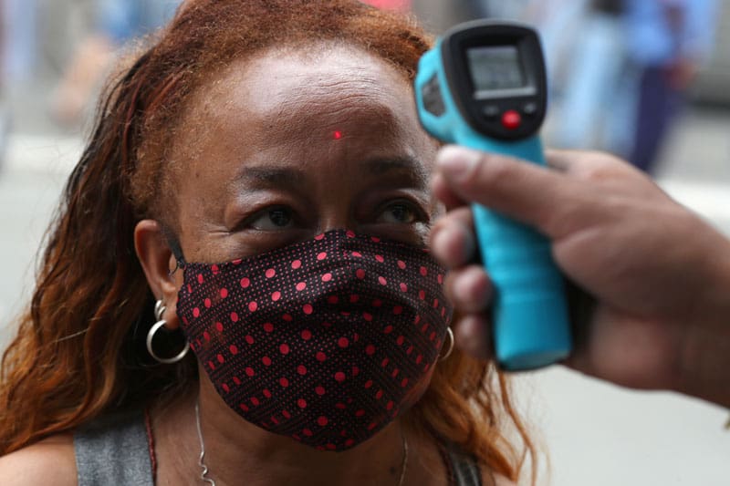 Un empleado verifica la temperatura de una mujer antes de que ingrese a una tienda en Sáo Paulo el 10 de junio de 2020, durante la pandemia de COVID-19. (CNS/Amanda Perobelli, Reuters)