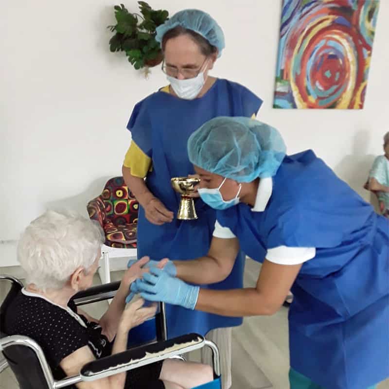 Yazmin Salazar, una cuidadora de la salud, y la hermana Brake distribuyen la Hostia consagrada a los residentes mientras usan guantes y mascarillas en abril del 2020. (Cortesía de Geraldine Brake / Panamá)