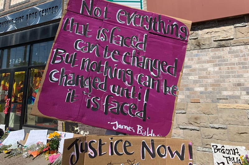 “No todo lo que enfrentamos se puede cambiar. Pero nada se puede cambiar hasta que lo enfrentemos.” Cita del activista y escritor James Arthur Baldwin se ve entre las señales cerca al memorial de George Floyd.