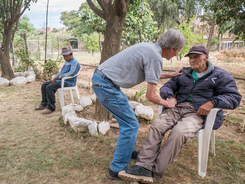 Dcha.: O’Donoghue consuela a Calixto Cejo, un anciano con problemas de audición y ciego de un ojo, en el centro de Cochabamba, Bolivia. Izq.: Andrés, un paciente descansa en el jardín. (NIle Sprague/Bolivia)