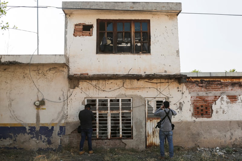 Fotógrafos toman fotografías del frente acribillado a balazos de una casa abandonada cerca de Aguililla, México, el 23 de abril de 2021. Los cárteles de la droga se han enfrentado entre sí y han bloqueado carreteras en la ciudad, lo que deja a los residentes sin poder viajar libremente y provocando escasez de todo, desde alimentos combustible. (Foto del CNS / Alan Ortega, Reuters)