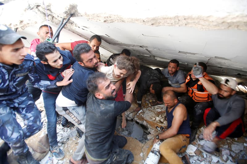 Los equipos de rescate cargan a Suzy Eshkuntana, de 6 años, mientras la sacan de los escombros de un edificio en el lugar de los ataques aéreos israelíes en la ciudad de Gaza el 16 de mayo de 2021 (foto del CNS / Mohammed Salem, Reuters).