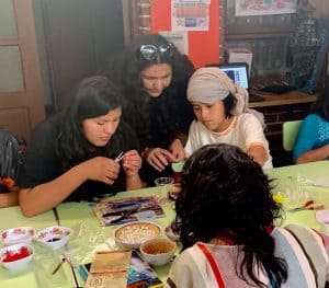 Lorena Simons (centro) enseña a las niñas en el refugio Our Home en Cochabamba, Bolivia, a hacer rosarios. (Matthew Sim / Bolivia)