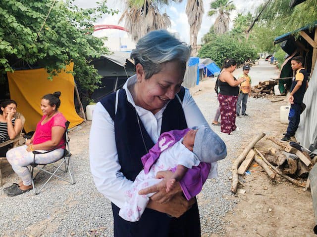 La hermana Norma Pimentel, directora ejecutiva de Caridades Católicas del Valle del Río Grande, aparece en una foto sin fecha sosteniendo a su ahijado en el campamento de migrantes en Matamoros, México, durante la pandemia de COVID-19. El nacimiento del bebé, como la mayoría de los partos en el campamento, representó un riesgo para la madre y el bebé, ya que la atención médica no es un hecho. (Foto del CNS / cortesía de la hermana Norma Pimentel)