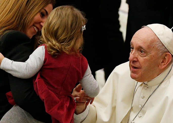 Dios nos da la fortaleza en la dificultad: El papa Francisco saluda a una mujer y un niño durante su audiencia general en el salón Pablo VI del Vaticano el 26 de enero de 2022. El papa explicó a la multitud que tenía un problema de inflamación en la rodilla derecha y que no iba a poder saludarlos como lo hace siempre. Esta vez, la multitud se acercó a él. (CNS photo/Paul Haring) 