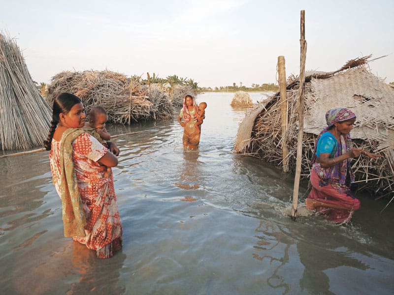 Hacia una ecología humana integral: Mujeres cargan niños al atravesar un área en Bogra, Bangladesh, donde las inundaciones han empeorado en los últimos años. El cambio climático ha afectado a personas en todo el mundo. (CNS/Bangladesh)