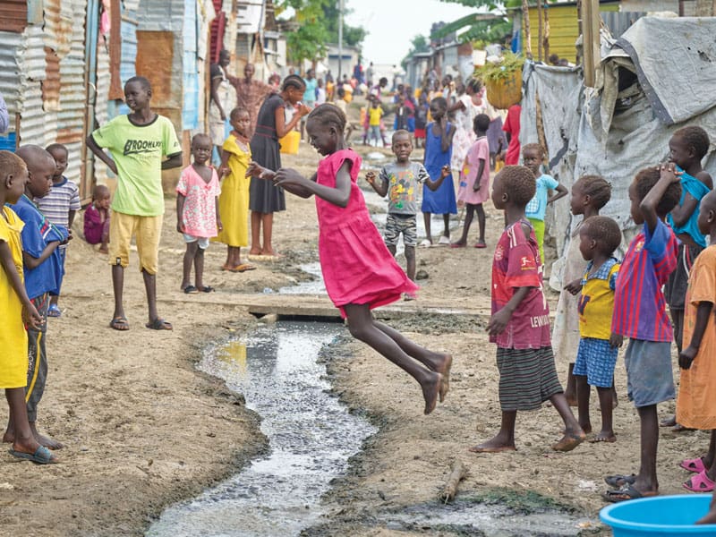 Niños juegan sobre una zanja de drenaje. Los residentes están protegidos por tropas de mantenimiento de la paz de la ONU. (Paul Jeffrey/Sudán del Sur)