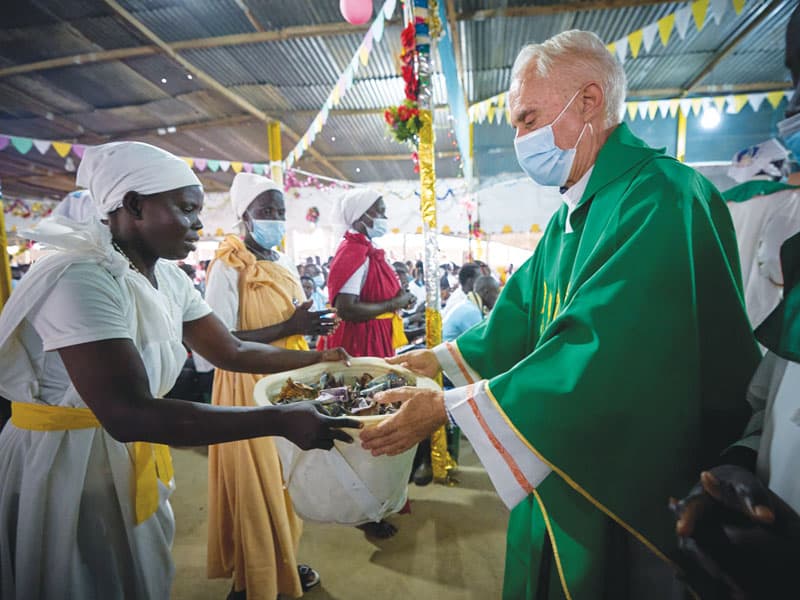 El padre Bassano recibe la ofrenda mientras celebra la misa en una capilla improvisada de madera de desecho y hojalata ondulada, reuniendo a los residentes shilluk, nuer y dinka.(Paul Jeffrey/Sudán del Sur)