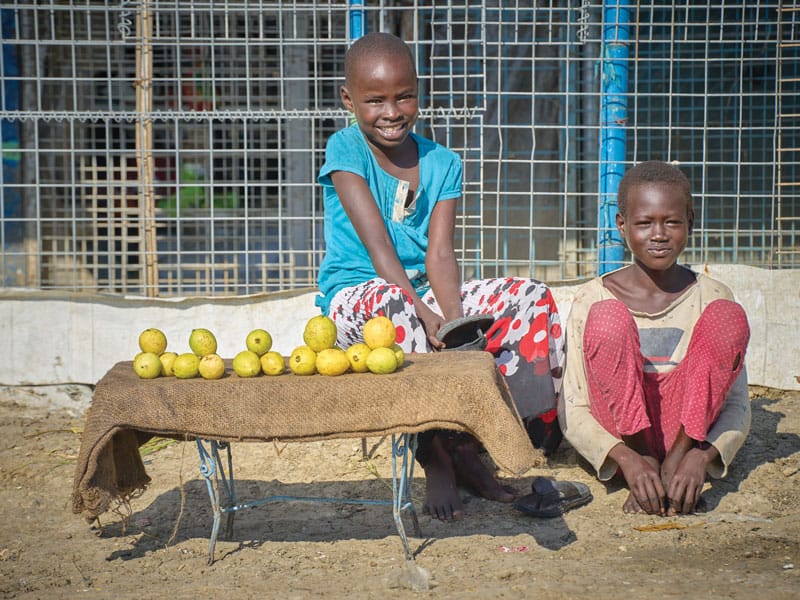 Estas dos niñas que viven en el campamento, aparecen vendiendo frutas. Ellas, junto a sus familiares, fueron desplazadas de sus hogares tras el estallido de la guerra civil en el 2013. (Paul Jeffrey/Sudán del Sur)