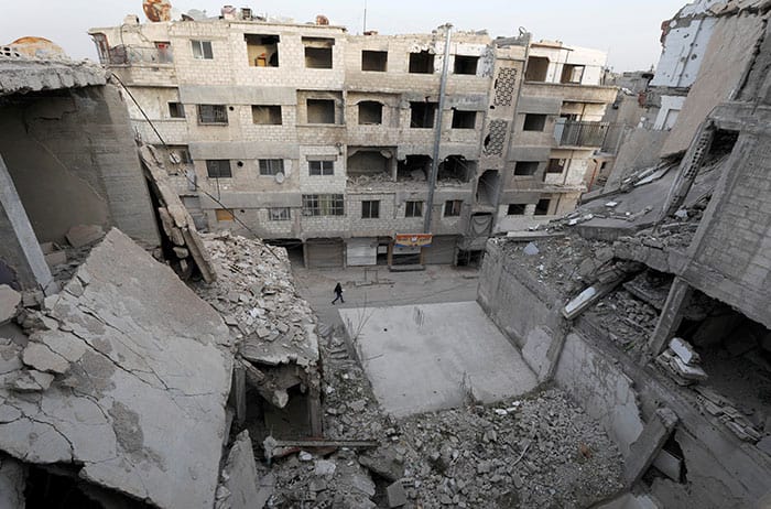 Un hombre pasa junto a edificios destruidos en Douma, Siria, el 9 de marzo de 2021. (Foto de CNS/Omar Sanadiki, Reuters)