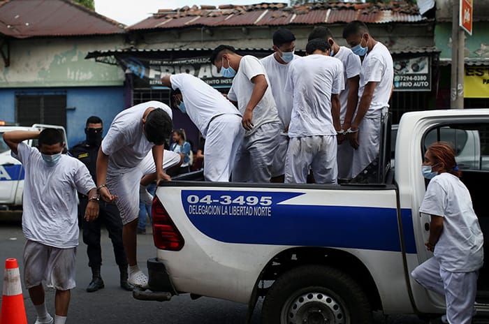 Hombres esposados salen de una camioneta de la policía afuera de un centro de detención en San Salvador, El Salvador, el 31 de marzo de 2022. Más de 12,000 salvadoreños han sido detenidos por el gobierno desde el 27 de marzo en un esfuerzo por combatir la violencia de las pandillas. (Foto CNS/José Cabezas, Reuters)