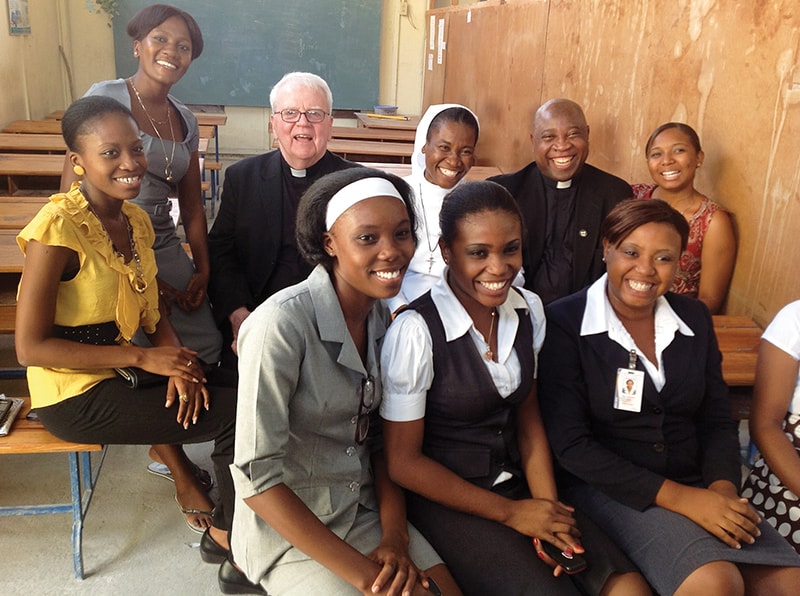 En un viaje a Haití en el año 2013, los Padres Maryknoll Michael Duggan y Romane St. Vil visitan una escuela que los Padres y Hermanos de Maryknoll ayudaron a reconstruir. (Cortesía de Romane St. Vil/Haití)