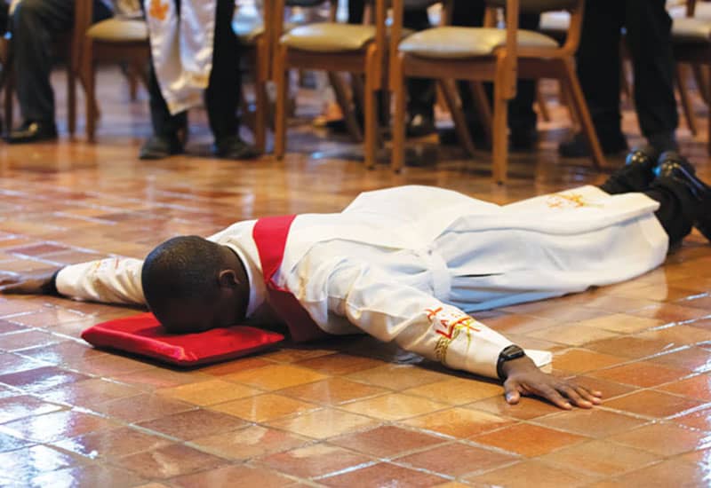El diácono John Siyumbu yace postrado ante el altar. (Octavio Durán/EE.UU.)
