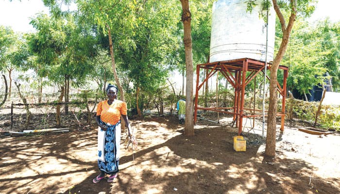 Una mujer de la Misión San Juan Bautista frente a un tanque de almacenamiento, parte de un proyecto de Maryknoll, que perfora pozos para proveer agua en Kibwezi devastada por la sequía. (Gregg Brekke/Kenya)