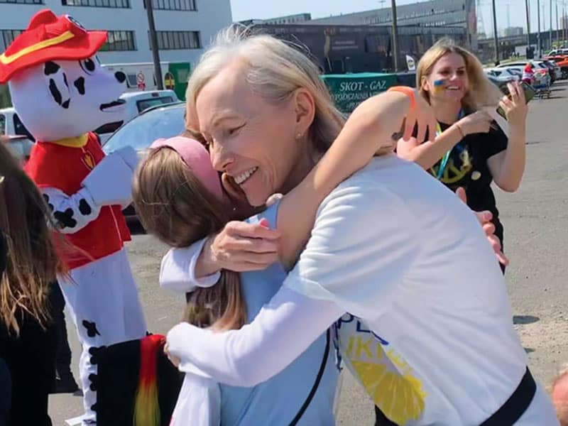 En un picnic, Pam Cibik, afiliada de Maryknoll, abraza a un niño refugiado de Ucrania mientras la coordinadora de voluntarios, Karolina Piskorz, sonríe al fondo. (Cortesía de Janet Alberti/Polonia)