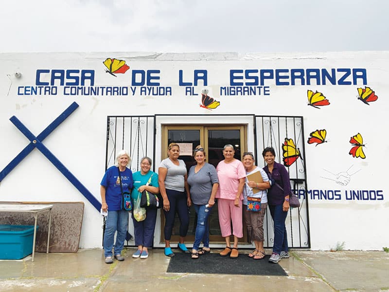 (De izquierda a derecha) Gail Kocourek, la Hermana Maryknoll Joy Esmenda, tres voluntarias, Dora Luz Rodríguez y la Hermana Natividad se reúnen en el centro de bienvenida Casa de la Esperanza en el lado mexicano de la frontera en Sasabe, Sonora. (Cortesía de Genie Natividad/EE.UU.)