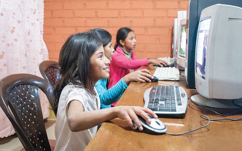Niñas estudiando en computadoras durante un programa de tutoría en la casa de Thanh y Vu en Punada, Cochabamaba. (Nile Sprague/Bolivia)