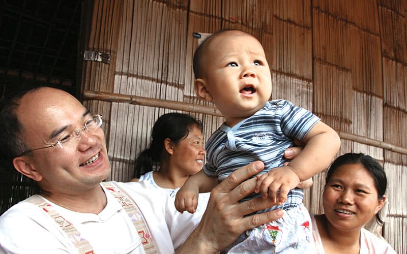 Hiep Vu alza a un bebé en la aldea Lahu en Chiang Dao,Tailandia, 2005. (Sean Sprague/Tailandia)