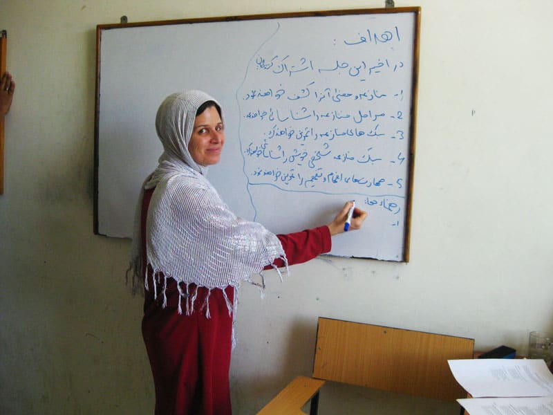 Kirstin De Mello escribe en la pizarra durante una capacitación en resolución de conflictos para estudiantes de oftalmología en Kabul, Afganistán, en 2016. (Cortesía de Maryknoll Lay Missioners)