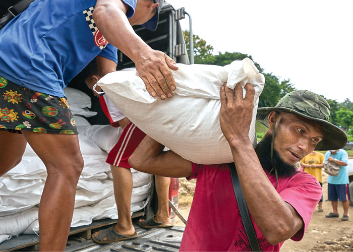 Los trabajadores de la aldea de Mae Sam Laep en Tailandia llevan sacos de arroz para personas desplazadas en Myanmar a los botes en el río Salween, que separa los dos países. (Paul Jeffrey/Tailandia)