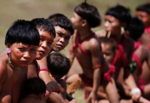 Los jóvenes yanomami observan cómo los miembros de un equipo médico del ejército brasileño examinan a los miembros de la tribu en el estado de Roraima el 1 de julio de 2020, durante la pandemia de COVID-19. (Foto del CNS/Adriano Machado, Reuters)