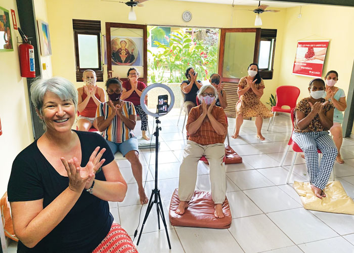 La misionera laica Kathy Bond (al frente) dirige una clase de yoga en AFYA. Ella enseña a miembros de la cooperativa y otros grupos habilidades terapéuticas que luego pueden ofrecer a otros. (Cortesía de Kathy Bond/Brasil)