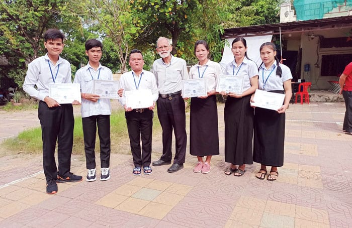 Sambath (segundo de la izquierda) y sus compañeros de clase que se graduaron en el 2022, con el Padre Charlie Dittmeier (centro) muestran con orgullo sus diplomas. (Sopor Lay, DDP/Camboya)