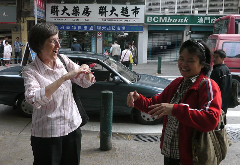 La Hermana Maryknoll Arlene Trant y una amiga sorda se saludan en las calles de Macao usando el lenguaje de señas. (Sean Sprague/Macao)