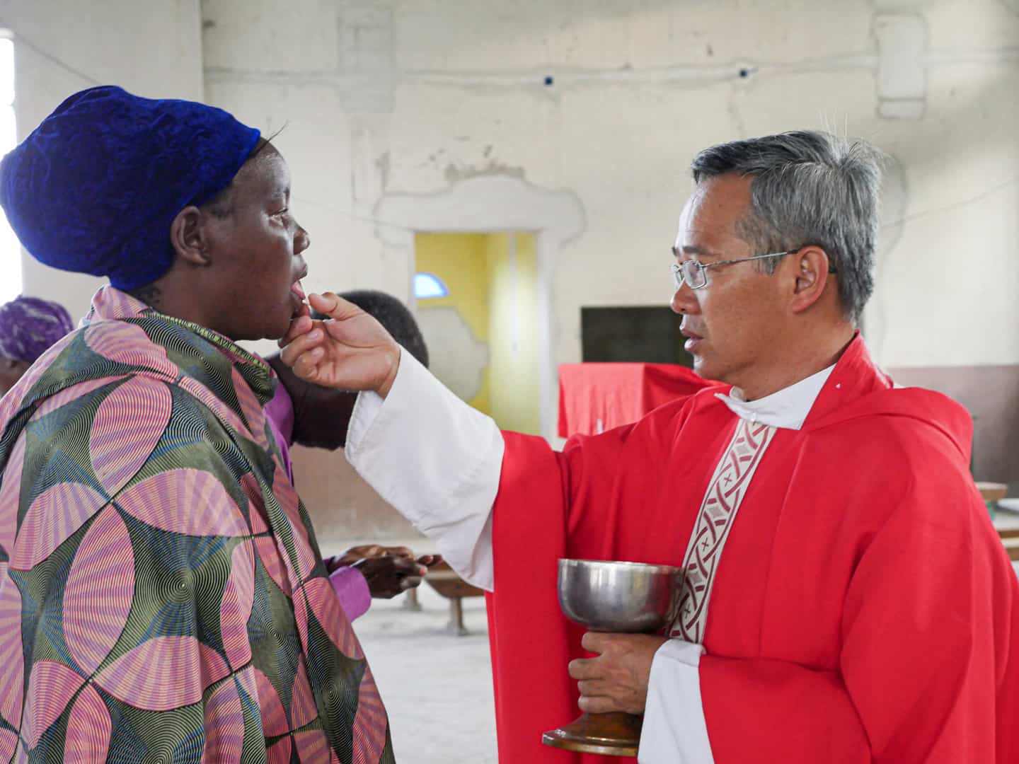 El padre Dinh da la comunión a una mujer en  la parroquia de Ndoleleji. 