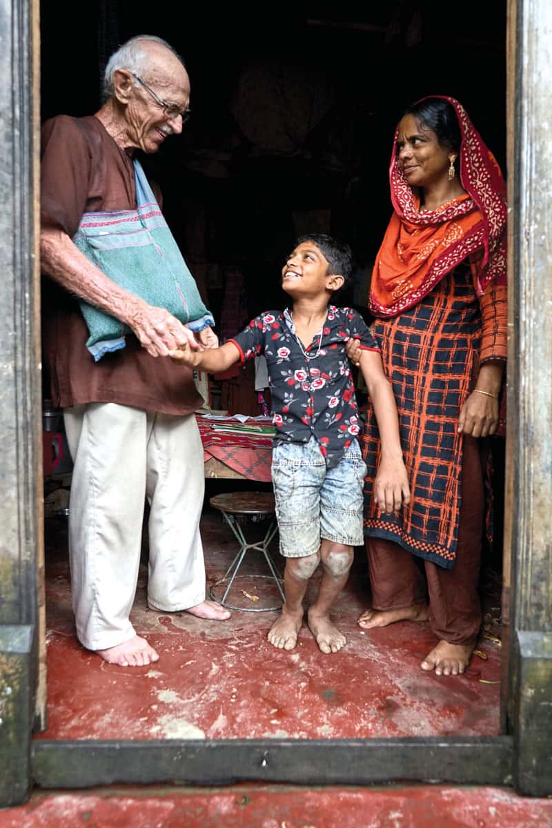 El Padre Maryknoll McCahill visita a la familia de Monna, un niño de 12 años que necesita ayuda de servicios de atención médica, en el pueblo de Nopara, Bangladesh. (Paul Jeffrey/Bangladesh)
