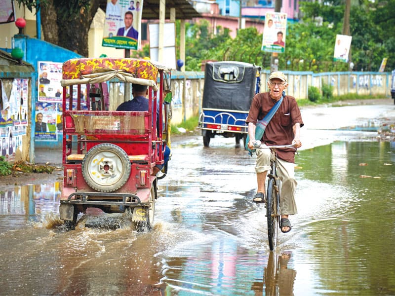 El misionero Maryknoll viaja principalmente en bicicleta, incluso bajo la lluvia. (Paul Jeffrey/Bangladesh)<br />
