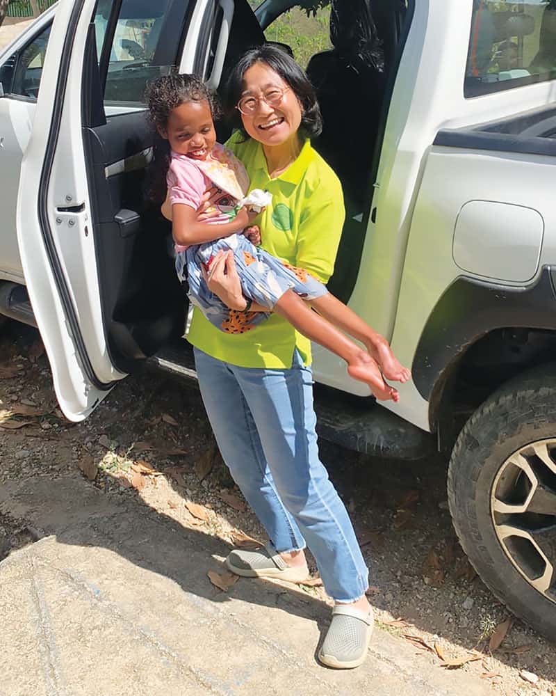 La Hermana Maryknoll Hyunjung Kim lleva a Rosalina a casa después de un programa semanal realizado en la clínica. La niña de 11 años de edad sufre de distrofia muscular. (Cortesía de Hyunjung Kim, M.M./Timor Oriental)