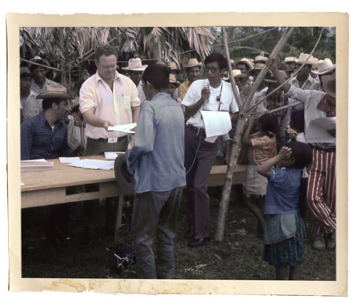 El Padre William Woods distribuye escrituras de tierras en la selva ixcana, donde ayudó a 2.000 familias a establecerse en cinco pueblos. La fotógrafa que tomó esta foto murió más tarde junto con al misionero laico John Gauker y el Padre Woods en el accidente aéreo. (Maryknoll Mission Archives/Selwyn Puig/Guatemala)