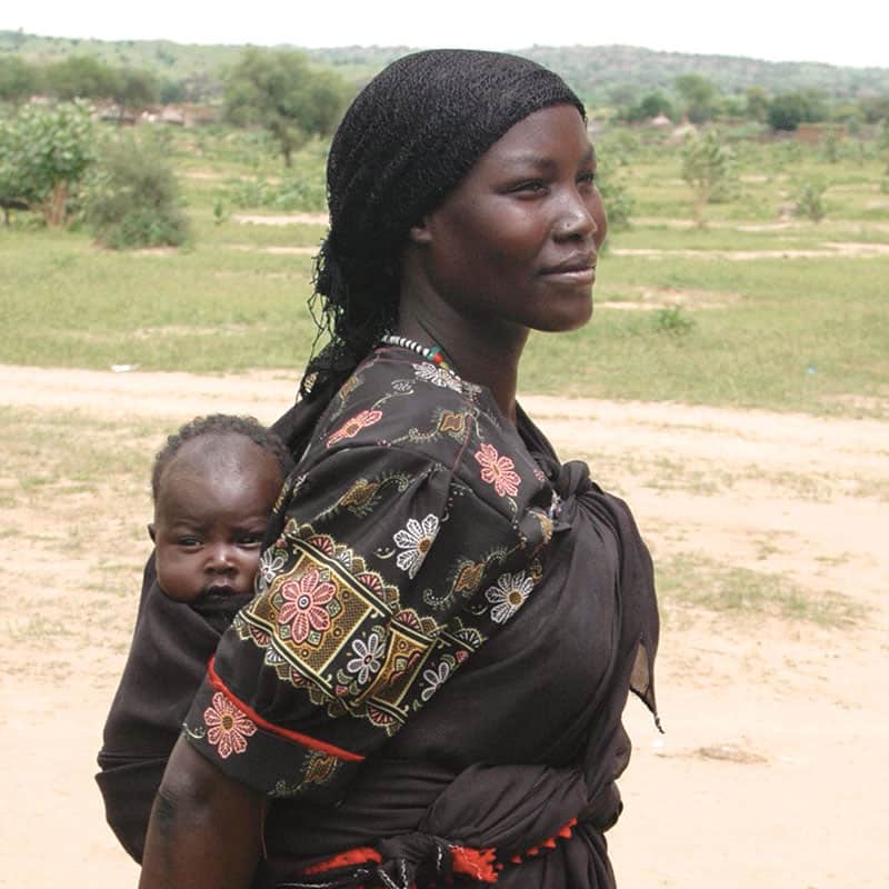 Una mujer sudanesa carga a su hijo en el campo de refugiados de Bredjing en Chad el 29 de agosto. Más de 200.000 refugiados sudaneses han huido a Chad para escapar de los ataques de las milicias árabes y las fuerzas gubernamentales sudanesas. (CNS/Stephen Steele/10 de septiembre de 2004) 