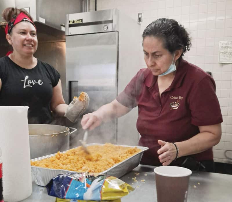 Claudia Díaz y Gloria Ibarra (derecha), feligresas de Cristo Rey, preparan comida caliente en la cocina de la parroquia para migrantes y refugiados de dos albergues de El Paso, Texas. (Cortesía de Gloria Ibarra/EE.UU.)