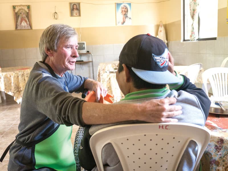 El misionero laico Maryknoll John O’Donoghue charla con un hombre discapacitado en Cochabamba, Bolivia. (Nile Sprague/Bolivia)