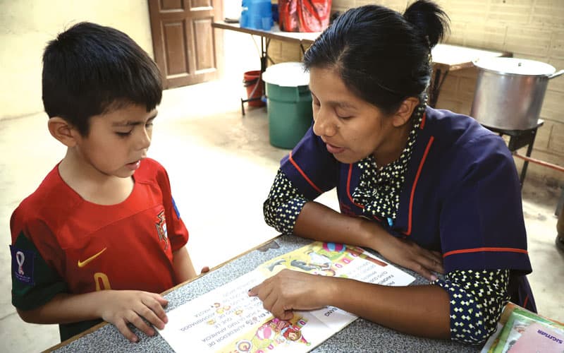 La tutora Beatriz Beltrán le enseña a leer a Ezequiel, un estudiante de primer grado que recibe tutoría en el proyecto Apoyo Escolar. (Adam Mitchell/Bolivia)