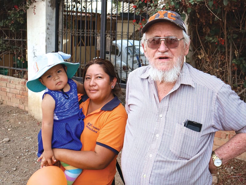 La coordinadora Jhovana Reyes, cargando a su hija Khyara, y el Padre Pablo se preparan en la capilla Nueva Vera Cruz para visitar las tres sedes del programa de Maryknoll Apoyo Escolar. (Adam Mitchell/Bolivia)